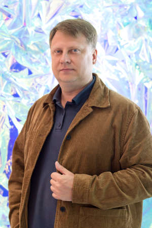 Portrait of an adult blond man corduroy jacket on the background of an abstract blue wall.
