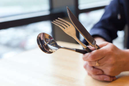 Table set fork, spoon, knife in women's hands on table.の写真素材