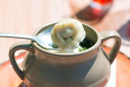 Dumplings in a clay pot, serving dishes in a street cafe, close-up.の写真素材