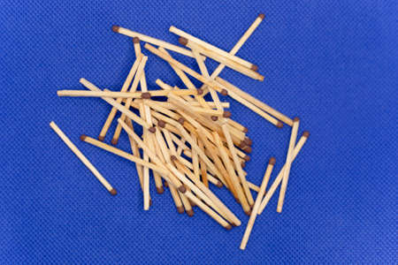 Wooden matches lie in a mountain, close-up. Blue backgroundの写真素材