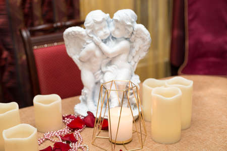 Angel figures, candles and rose petals, romantic dinner in a restaurant.の写真素材