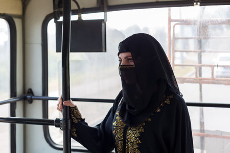 A Muslim woman in national clothes rides on public transport.の写真素材