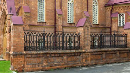 A high beautiful metal fence around old red brick building.の写真素材
