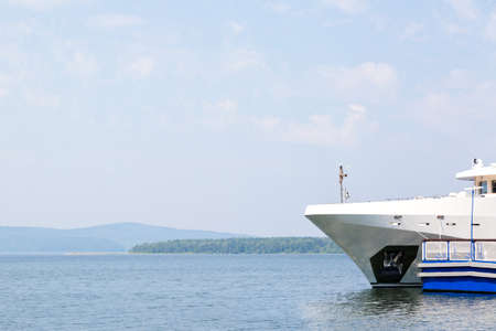 A large white pleasure boat with tourists sails from the shore.
