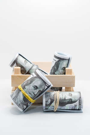 A small wooden box with paper dollar bills on a white background.の写真素材