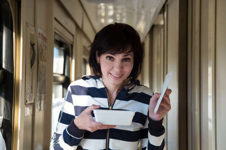 An adult woman on the train is walking down the corridor with an open package of instant noodles.の写真素材