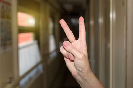Woman's hand with raised fingers in a train car.