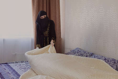 Muslim woman doing housework. Refueling and cleaning pastels after sleep.の写真素材