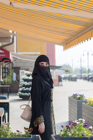 Young slender Muslim woman in black clothes streets of Dubai.