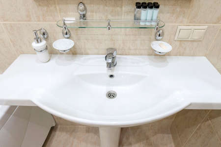 Bathroom with white sink and toilet. White bathrobes guests hang on the wall.
