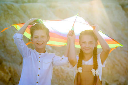 A boy and a girl are hiding from the rays of the sun under a kite.の写真素材