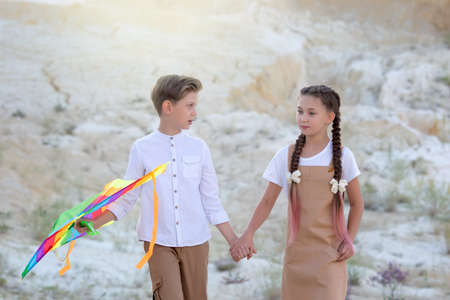 A boy and girl walk holding hands, the boy carries a kite.の写真素材