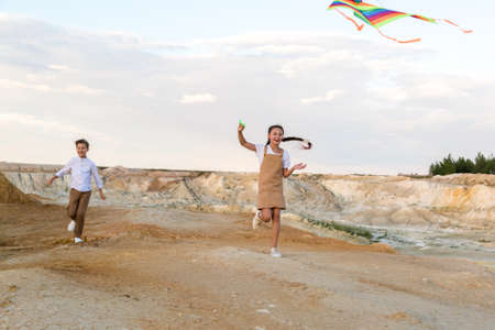Children run holding a flying kite by the fishing line.の写真素材