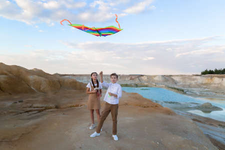 Brother and sister fly kite standing near the river.の写真素材