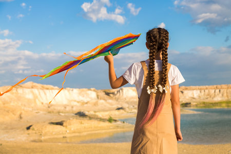 A teenage girl with a kite climbing to the top of the mountain looks into the distance.の写真素材