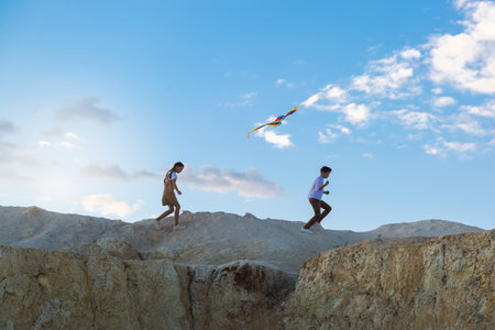 Children run with a kite on the slope of a high mountain, copy space.の写真素材