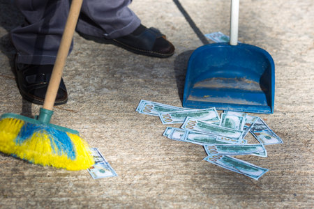 Dollars on the ground are collected with a brush scoop. Dirty money fight concept.の写真素材