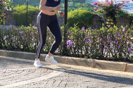 legs of a running athlete in sports white shoes background of a flowerbed with flowers.