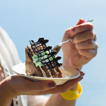 Chocolate cake white plate in female hands.