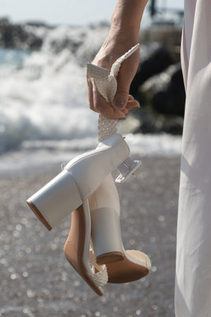 White shoes with a heel in a female hand, close-up.の写真素材