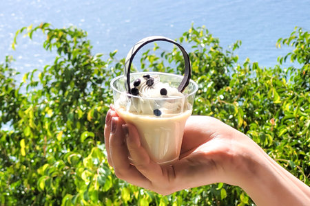 Sweet dessert cake in a transparent glass person's hand.の写真素材