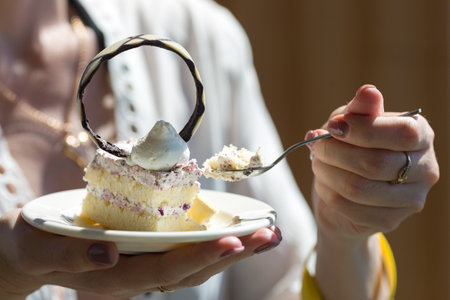 Sweet morning dessert in a restaurant woman holds a piece of cake.の写真素材