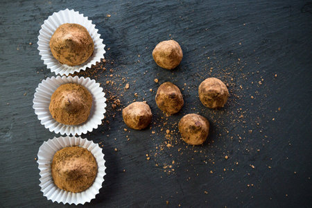 Truffle candies liberally sprinkled with cocoa in white substrates a black trayの写真素材