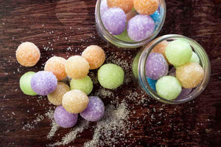Colored round candy balls sprinkled with sugar glass jar and on a wooden table.の写真素材