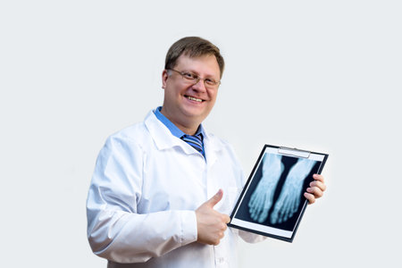 Male doctor examines an x-ray white gray background.の写真素材