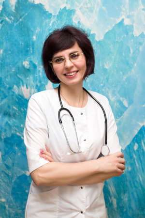 Portrait of a female doctor 40-44 years old near a blue wall.の写真素材