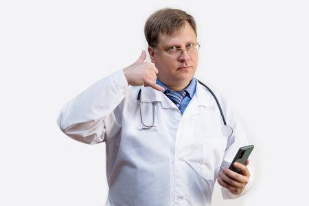The doctor shows with gestures that he is calling on a smartphone, the concept of a medical consultation on the phone.の写真素材