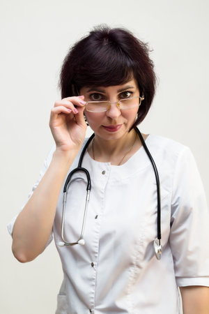 Woman doctor through glasses looks at the camera, close-up.の写真素材