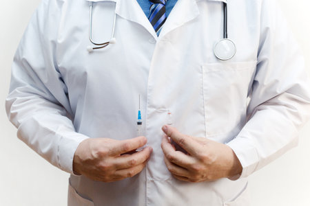 Syringe and ampoule on the background of a medical white coat.の写真素材