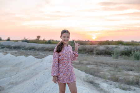 A teenage girl in a summer dress is photographed at sunset.の写真素材