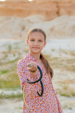 A teenage girl plays with snake holding it in her hands. Children and snakes in the wild.の写真素材