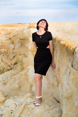 Girl in black dress smiling on the edge of a cliff.の写真素材