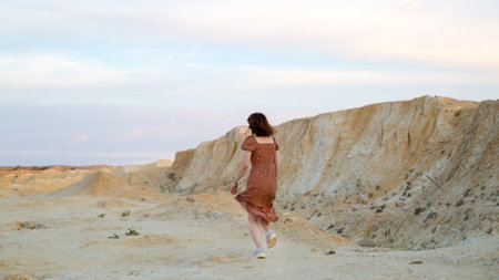 A girl in a dress runs through the mountains view from the back. The concept getting away from trouble and stress.の写真素材