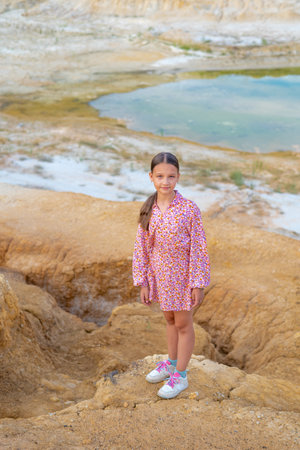 Girl walks on clay mountains outside city.の写真素材