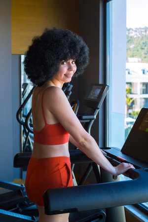 Girl with lush curly black hair in red clothes in the gym.の写真素材