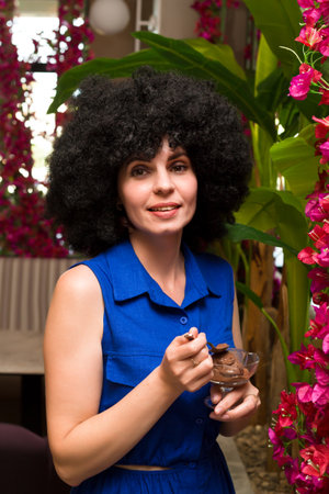 middle aged woman with curly black hair eats ice cream.の写真素材