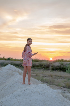 A teenage girl in a summer dress photographed at sunset.の写真素材