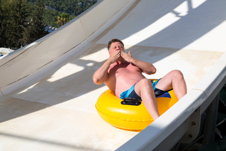A man riding a water slide blows a kiss.の写真素材