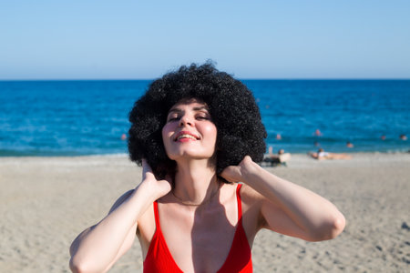 Brunette with curly hair red clothes smiles having fun on the beach.の写真素材