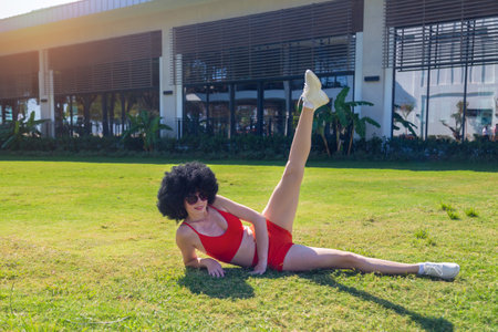 Girl athlete lying on the lawn doing leg exercises.