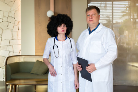 Portrait of male and female doctors operating gowns in the lobby of clinic.の写真素材