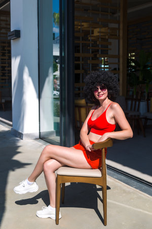 A woman with black curly hair sits chair near the entrance to a store.の写真素材