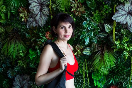 Girl athlete with bag on her shoulder against the background of a wall of flowers.の写真素材