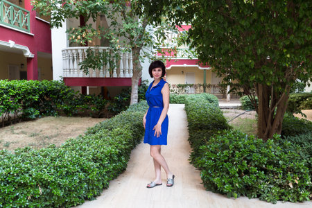 Adult brunette woman blue dress in a city garden.の写真素材