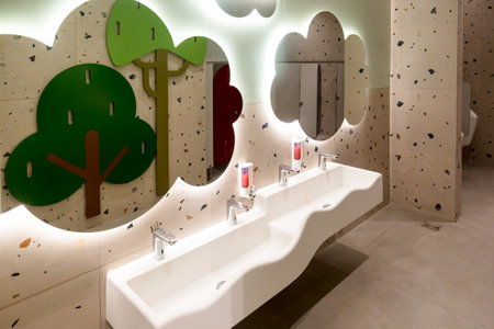 Bathroom interior with white washbasins and decorative trees.の写真素材