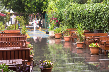 Empty street cafe after rain, wet restaurant furniture on the street.